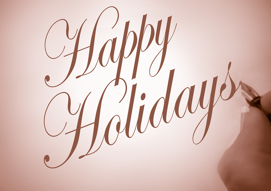 Person writing Happy Holidays in calligraphy script with sepia tone